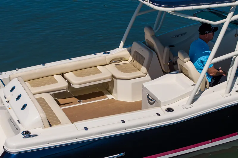 Slide: The Image of 2017 Chris-Craft Calypso 26 boat interior with beige seating and a person at the helm. - 5