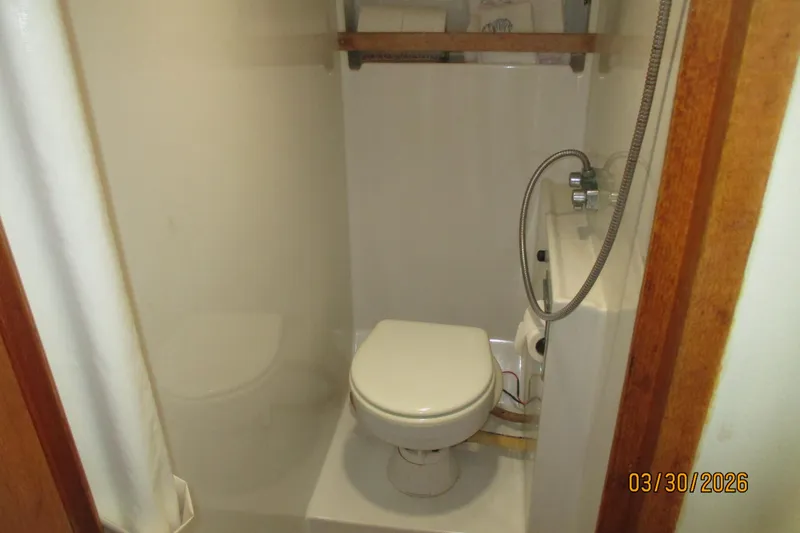 Slide: The Image of Compact bathroom in a 1989 Chris Craft 427 boat, featuring a toilet and shower. - 20