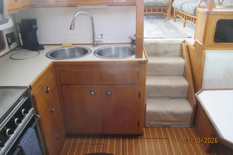 Slide: The Image of 1989 Chris Craft 427 yacht kitchen with wooden cabinetry, dual sinks, and stairs. - 21