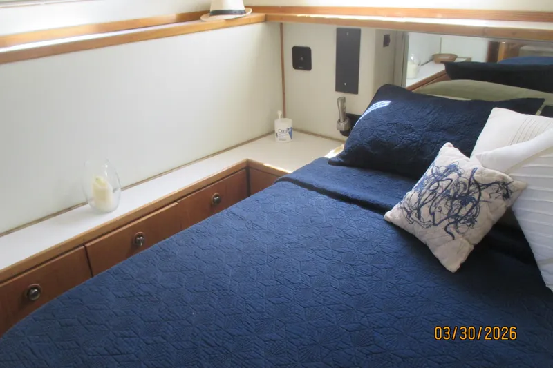 Slide: The Image of Cozy cabin interior of 1989 Chris Craft 427 yacht with blue bedding and decorative pillows. - 24