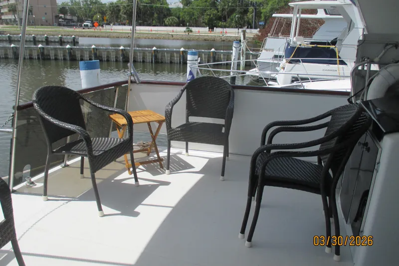 Slide: The Image of Deck of 1989 Chris Craft 427 yacht with chairs and table, docked by the water. - 4