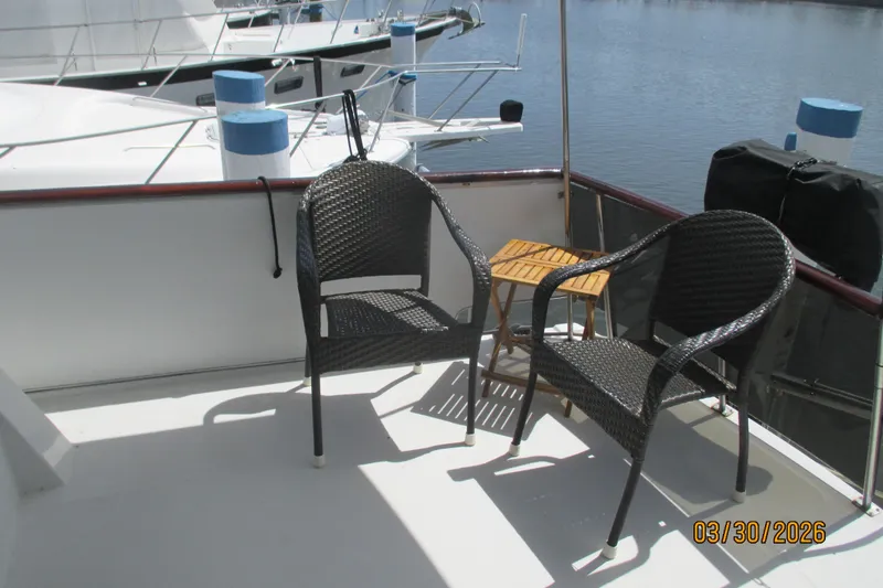 Slide: The Image of Outdoor seating on 1989 Chris Craft 427 yacht deck, featuring two wicker chairs and a small table. - 5