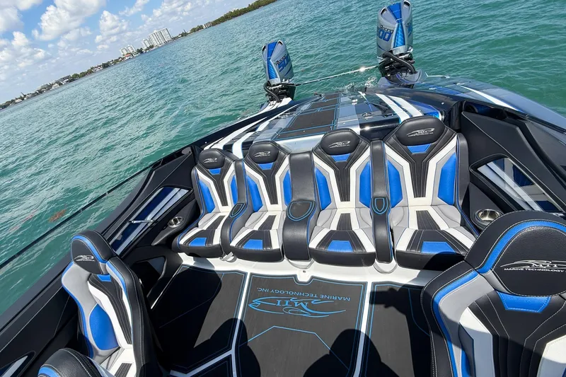 Slide: The Image of 2024 MTI 440X boat with sleek blue and black seating on open water. - 5