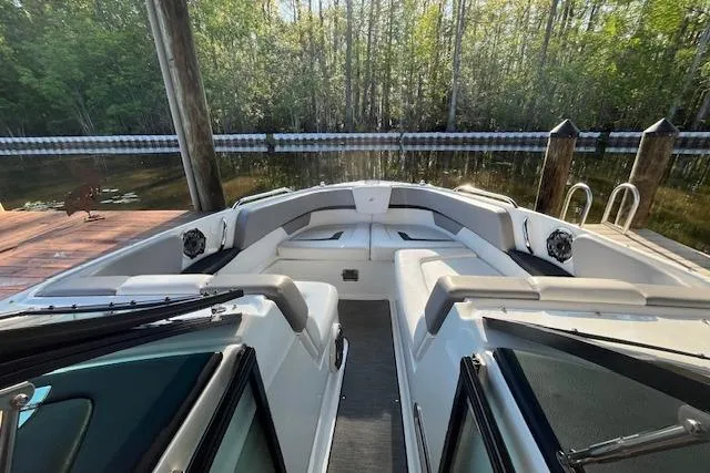 Slide: The Image of 2020 Four Winns H290 OB boat interior with seating, docked by a wooded shoreline. - 4