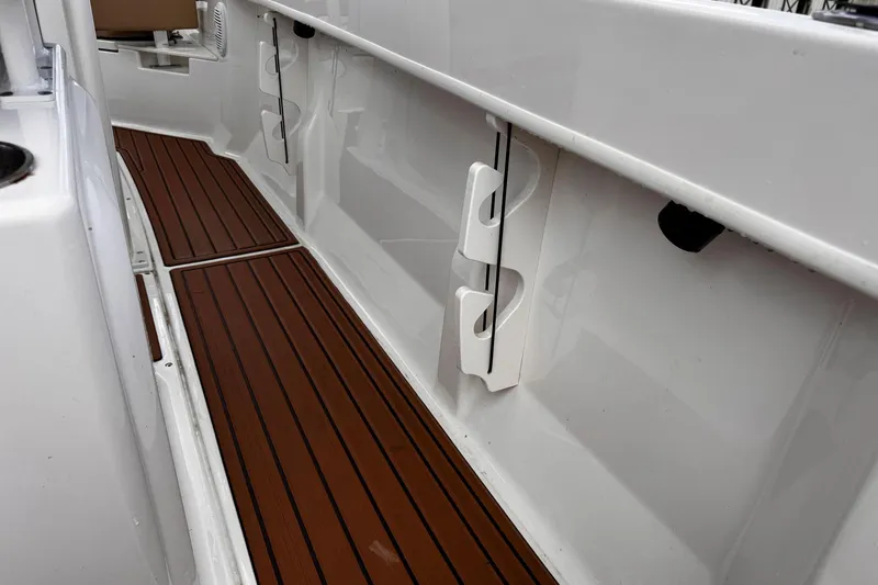 Slide: The Image of 2023 Bayliner Trophy T20CC boat interior with wood-style flooring and rod holders. - 19