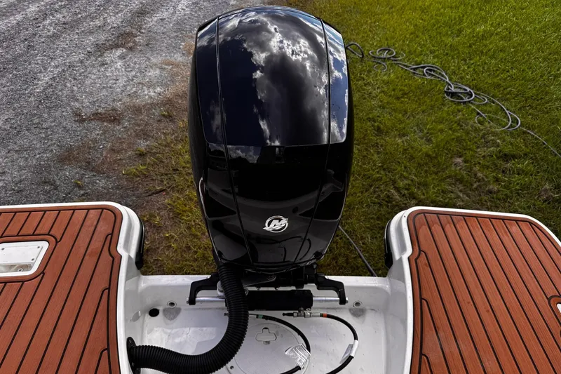 Slide: The Image of 2023 Bayliner Trophy T20CC boat engine with wooden deck, grass, and gravel background. - 24
