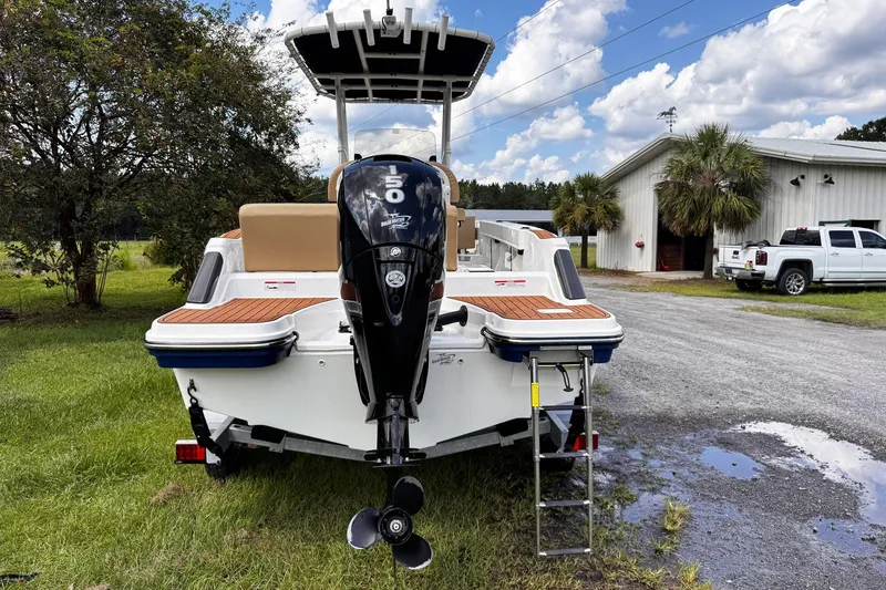 Slide: The Image of 2023 Bayliner Trophy T20CC boat with outboard motor, parked outdoors near a building. - 4