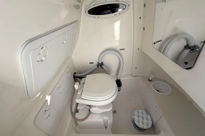 Slide: The Image of Interior of 2022 Sea Pro 239 Center Console boat's compact bathroom with toilet and sink. - 16