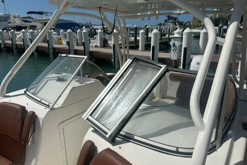 Slide: The Image of 2019 Century 24 Resorter boat interior at marina, featuring open windshield and brown seating. - 26