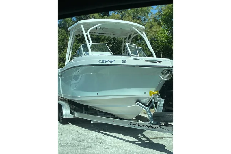 Slide: The Image of 2019 Century 24 Resorter boat on trailer, parked outdoors, with trees in the background. - 37