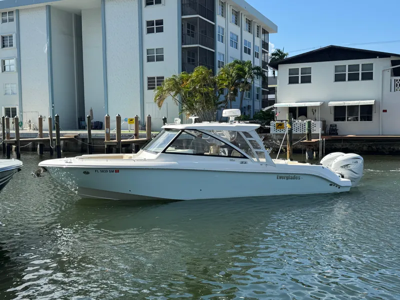 Slide: The Image of 2019 Everglades 340 Dual Console boat docked near waterfront buildings. - 24