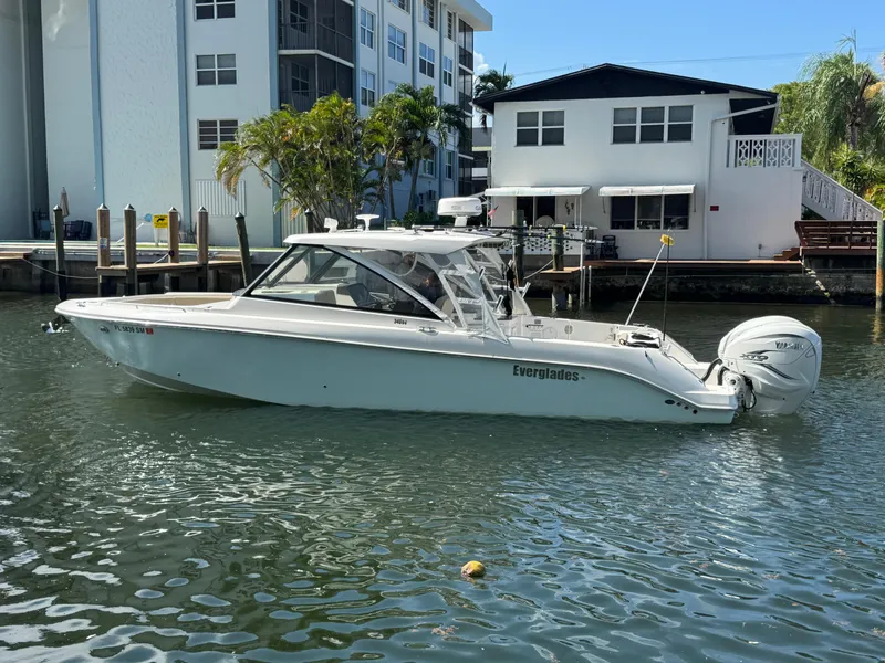 Slide: The Image of 2019 Everglades 340 Dual Console boat docked near waterfront homes. - 25