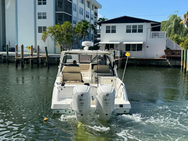 Slide: The Image of 2019 Everglades 340 Dual Console boat navigating a canal near residential buildings. - 27