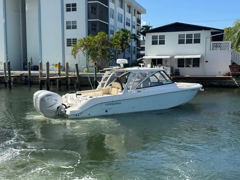 Slide: The Image of 2019 Everglades 340 Dual Console boat cruising near waterfront homes. - 29