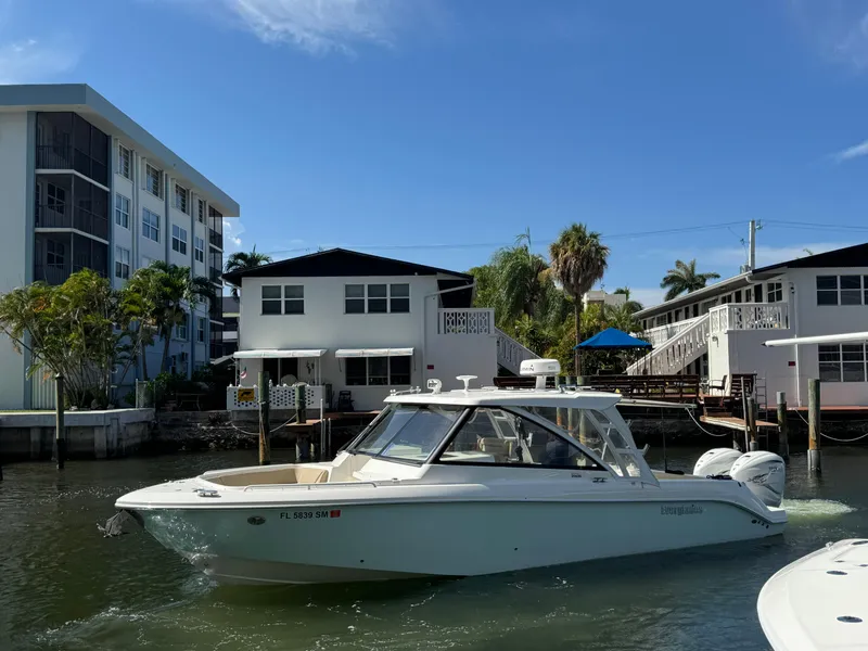 Slide: The Image of 2019 Everglades 340 Dual Console boat cruising near waterfront homes under a clear blue sky. - 39
