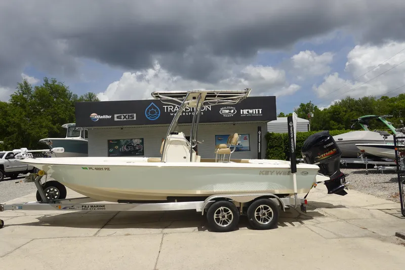 The Image of 2015 Key West 230 Bay Reef boat on trailer at dealership under cloudy sky. - 1