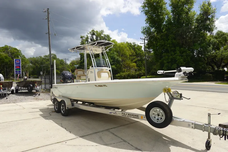 Slide: The Image of 2015 Key West 230 Bay Reef boat on trailer, parked outdoors under cloudy sky. - 3