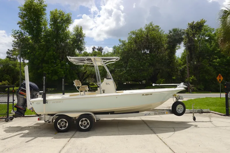 Slide: The Image of 2015 Key West 230 Bay Reef boat on trailer, parked outdoors with lush greenery. - 4