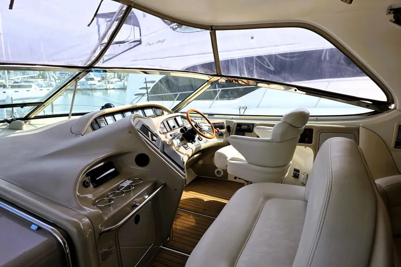 Slide: The Image of 1999 Sea Ray Sundancer 540 yacht interior with helm, leather seating, and marina view. - 20