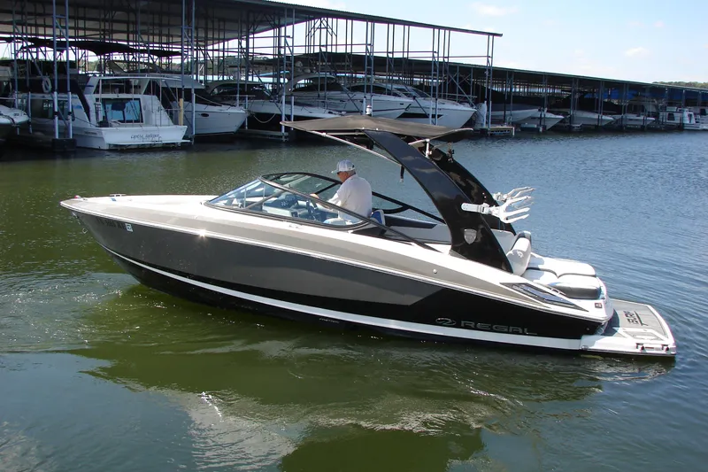 Slide: The Image of 2017 Regal 2300 RX Surf boat docked in marina, sleek design, calm water. - 12