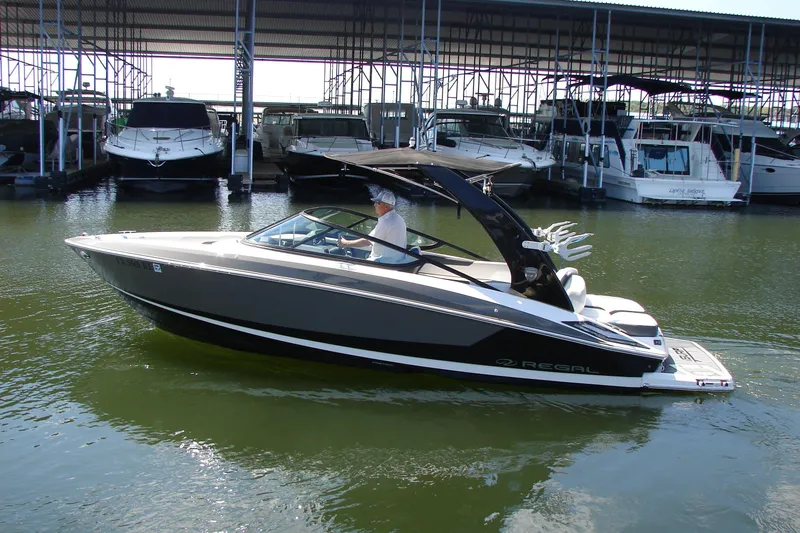 Slide: The Image of 2017 Regal 2300 RX Surf boat docked in a marina, sleek design, calm waters. - 13
