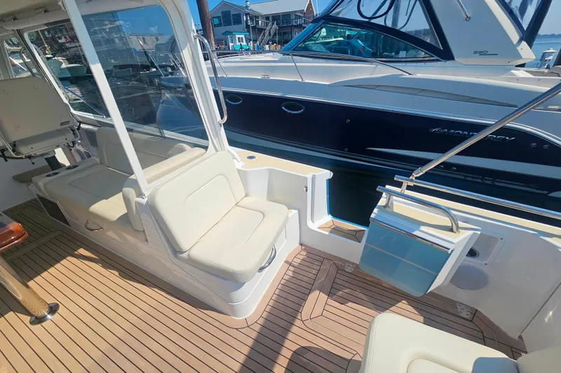 Slide: The Image of 2023 MJM 35 boat interior with seating and wooden deck, docked beside another vessel. - 19