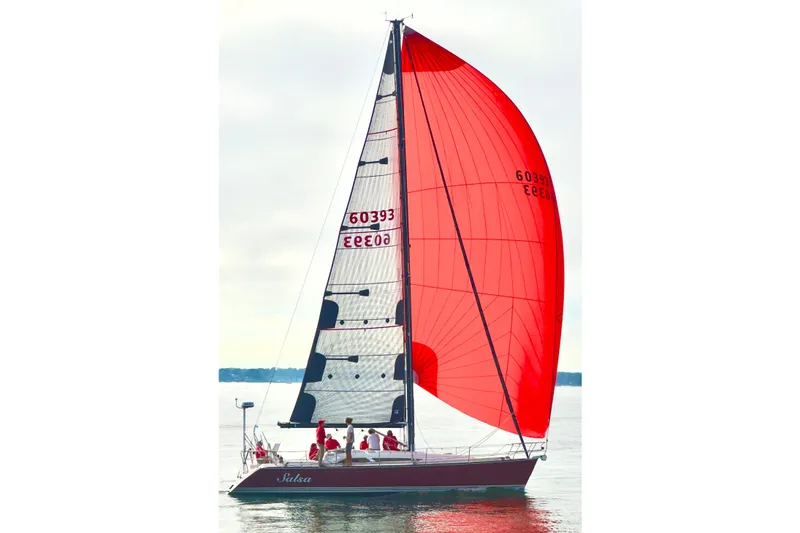 The Image of Sailing yacht C&C 121 from 2004 with vibrant red spinnaker on calm waters. - 0