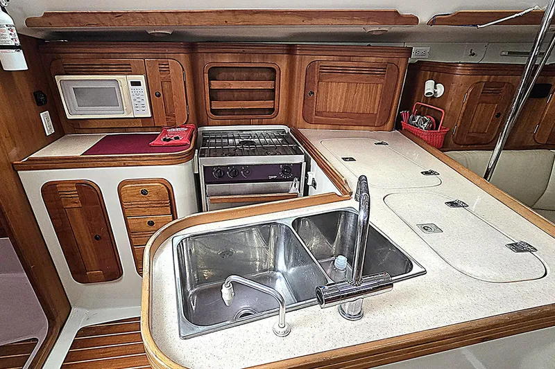 Slide: The Image of Modern yacht kitchen with dual sinks, stove, microwave, and wooden cabinetry in a 2004 C&C 121. - 6