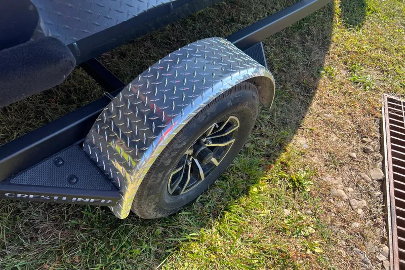Slide: The Image of Trailer wheel of 2026 Crestliner 1650 Kodiak on grass, featuring diamond plate fender. - 3