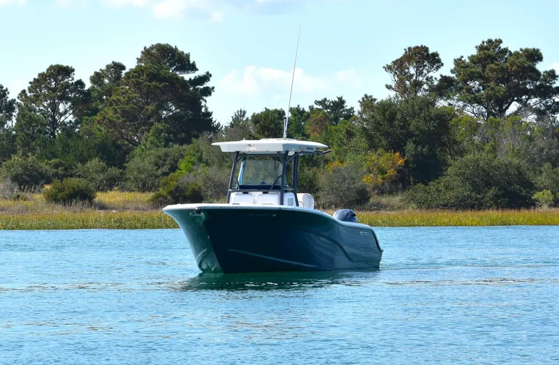 Slide: The Image of 2020 Sea Fox 266 Commander boat on calm water near a forested shoreline. - 2