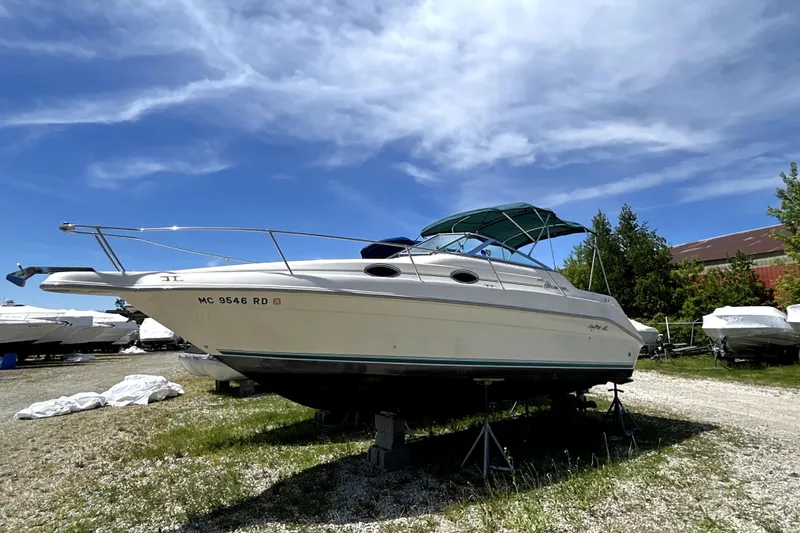 The Image of 1995 Sea Ray 250 Sundancer boat on stands under a clear blue sky. - 0