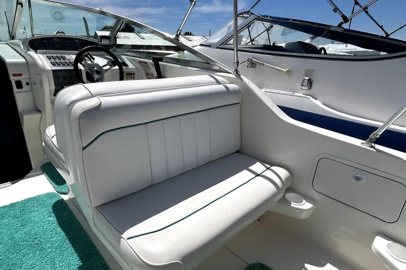 Slide: The Image of Interior view of a 1995 Sea Ray 250 Sundancer boat with white seating and dashboard. - 20
