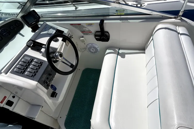 Slide: The Image of 1995 Sea Ray 250 Sundancer helm with steering wheel, controls, and white seating. - 23