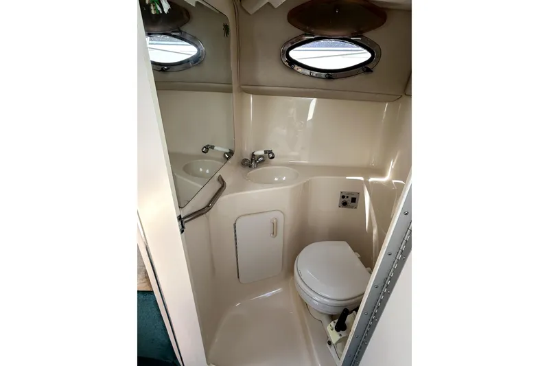 Slide: The Image of 1995 Sea Ray 250 Sundancer boat bathroom with sink, toilet, and porthole window. - 27