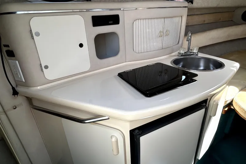 Slide: The Image of 1995 Sea Ray 250 Sundancer boat kitchenette with sink, stove, and storage cabinets. - 30