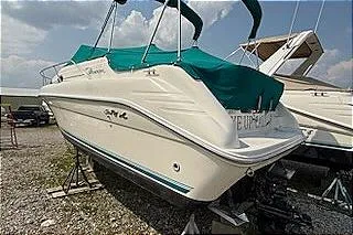 Slide: The Image of 1995 Sea Ray 250 Sundancer boat with teal cover, parked on gravel. - 4