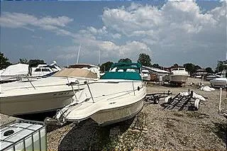 Slide: The Image of 1995 Sea Ray 250 Sundancer boat in a marina with other vessels under a cloudy sky. - 5