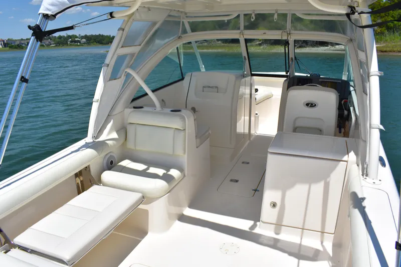 Slide: The Image of 2012 Pursuit DC 265 Dual Console boat interior with seating and helm, on calm water. - 15