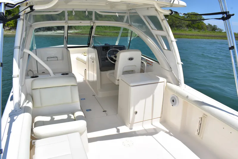 Slide: The Image of 2012 Pursuit DC 265 Dual Console boat interior with seating and helm, on calm water. - 16