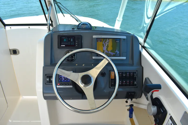 Slide: The Image of 2012 Pursuit DC 265 Dual Console boat dashboard with steering wheel and navigation system. - 18