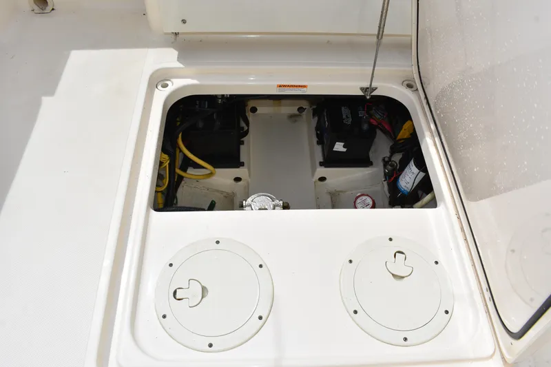 Slide: The Image of 2012 Pursuit DC 265 Dual Console boat storage compartment with visible wiring and components. - 21