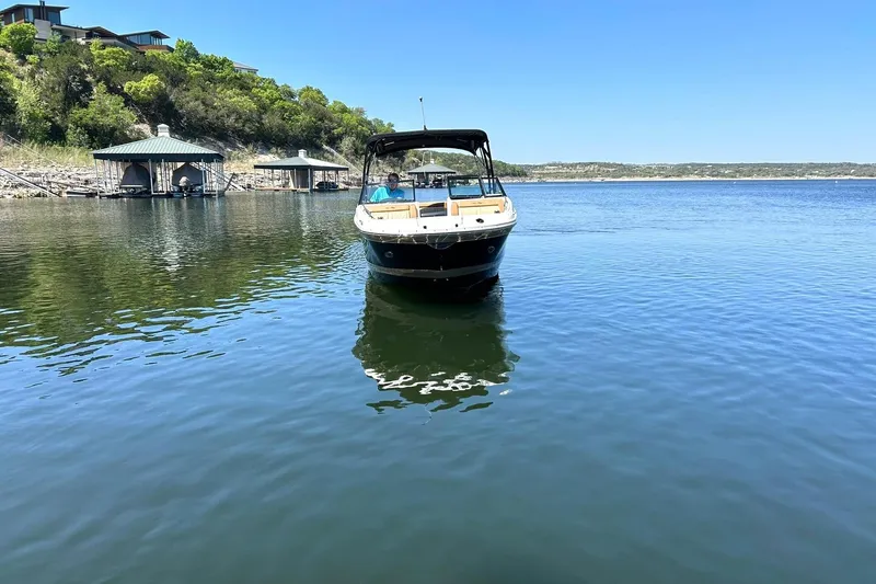 Slide: The Image of 2015 Sea Ray 270 Sundeck boat on calm lake near docks and lush hillside. - 11