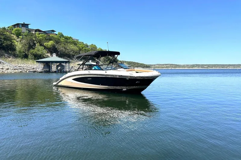 Slide: The Image of 2015 Sea Ray 270 Sundeck boat on a serene lake with hillside homes. - 13