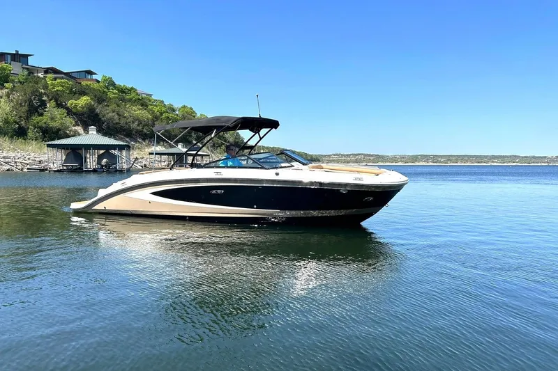 Slide: The Image of 2015 Sea Ray 270 Sundeck boat on a serene lake with clear blue skies. - 15