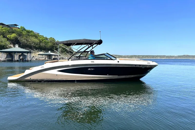Slide: The Image of 2015 Sea Ray 270 Sundeck boat on calm water, with scenic shoreline background. - 16
