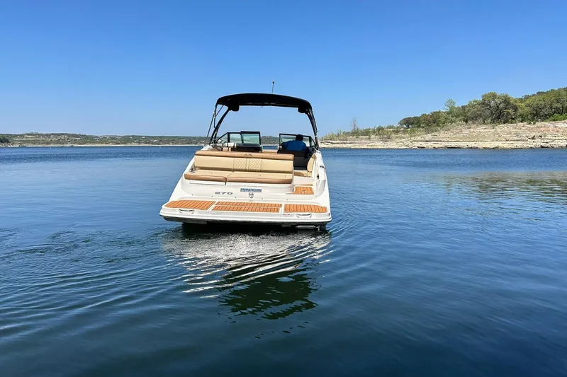 Slide: The Image of 2015 Sea Ray 270 Sundeck boat cruising on a serene lake under clear blue skies. - 22