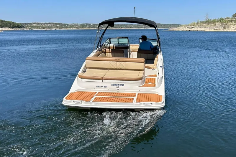 Slide: The Image of 2015 Sea Ray 270 Sundeck cruising on a serene lake under clear blue skies. - 23