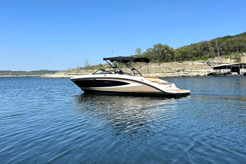 Slide: The Image of 2015 Sea Ray 270 Sundeck boat on a serene lake with clear blue skies. - 25