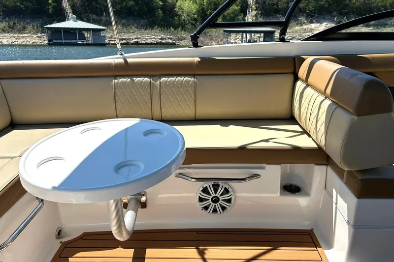 Slide: The Image of 2015 Sea Ray 270 Sundeck interior with cushioned seating and round table on a sunny day. - 33