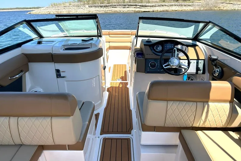 Slide: The Image of 2015 Sea Ray 270 Sundeck interior with tan seating and modern dashboard on a sunny day. - 43
